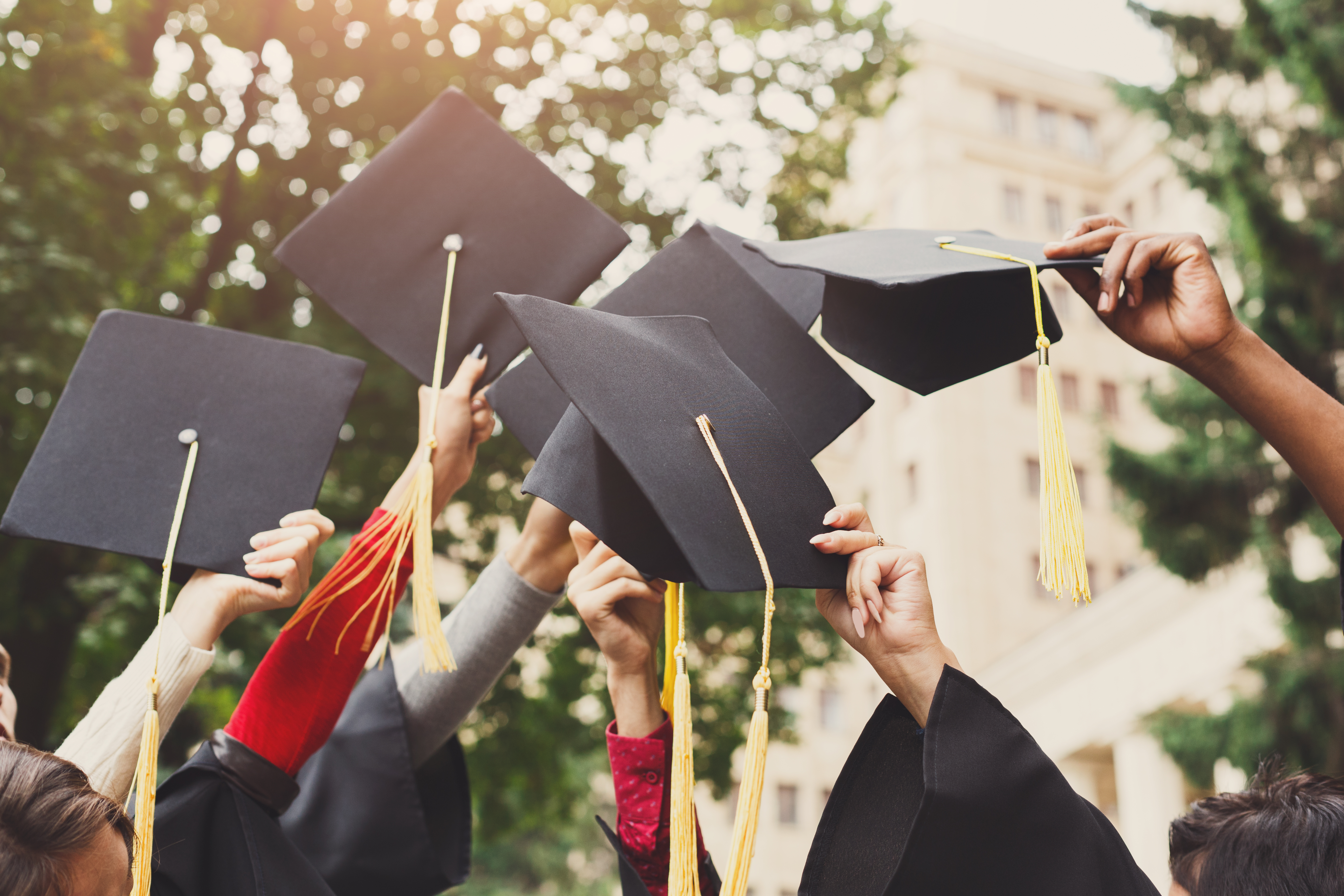 Students holding graduation caps in the air