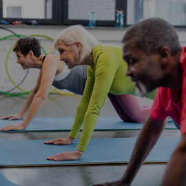 Two female's and a male doing yoga