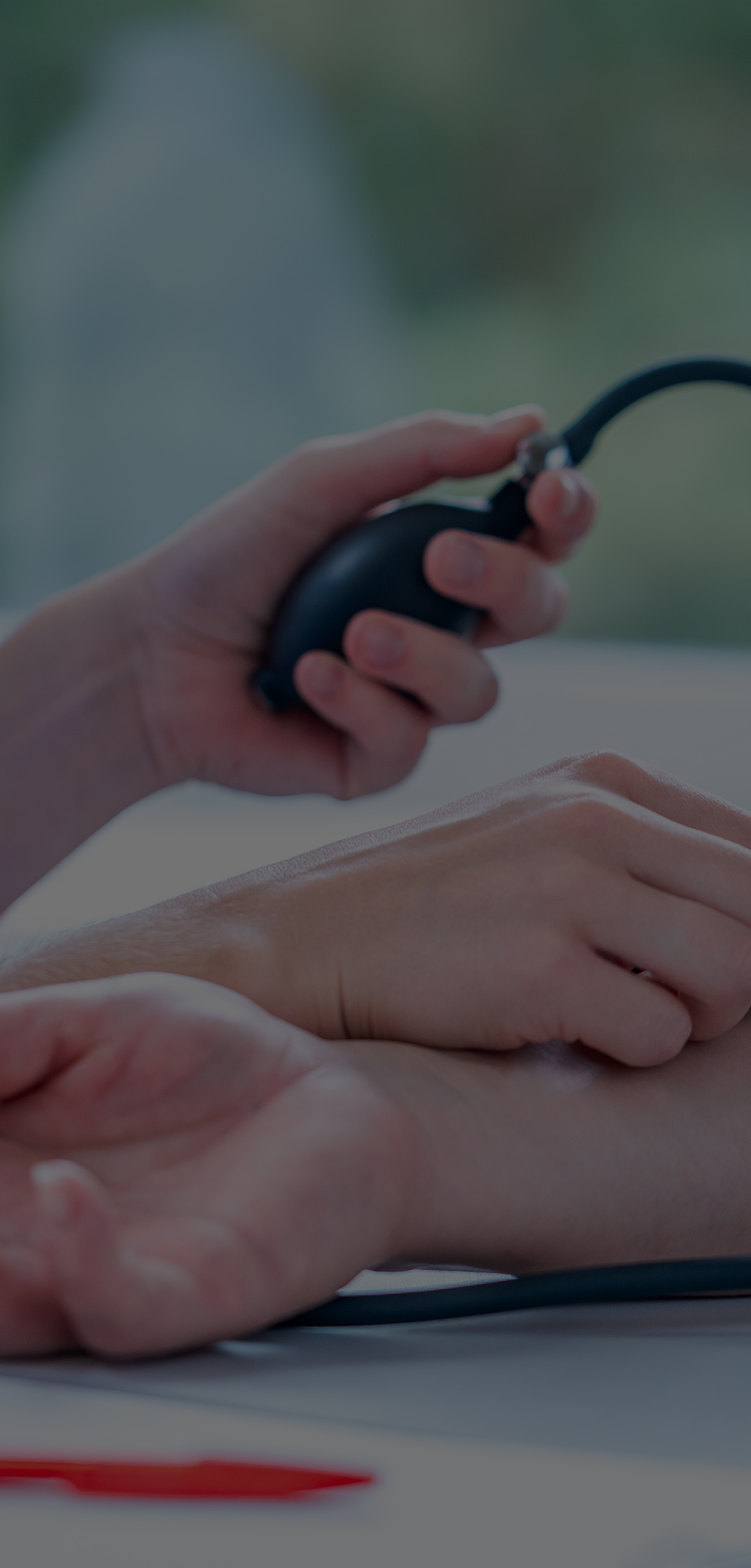 A doctor holding a patients hand while trying to take their blood pressure.