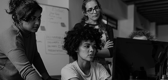 Female workers gathered around computer.