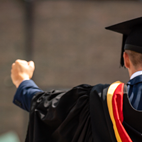 Student celebrating their graduation in their graduation robes.