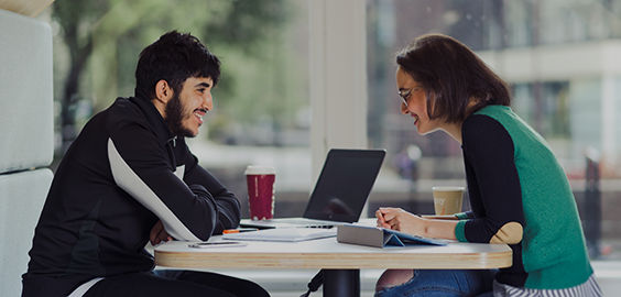 a group of people sitting at a table using a laptop computer