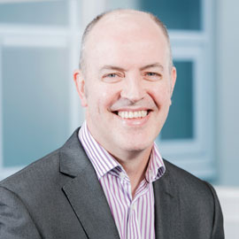 a man wearing a suit and tie smiling at the camera