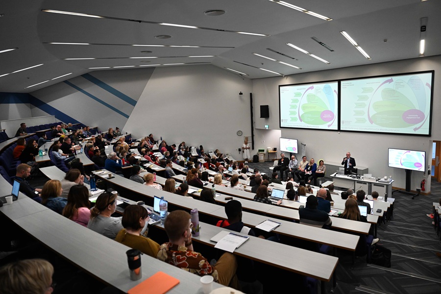 A large lecture theatre full of people looking ahead to a speaker and panel