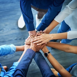 Group of people putting their hands together in the centre of them