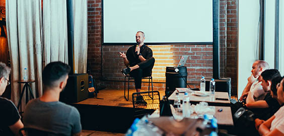 Male speaker on a stage with a microphone talking to an audience