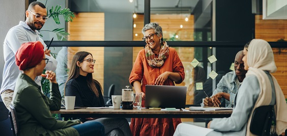A group of colleagues positioned around a table in an office space