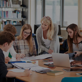 Group of students with member of staff supporting them with their work