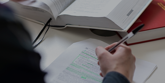 Close-up of na student making notes, using a black biro pen.