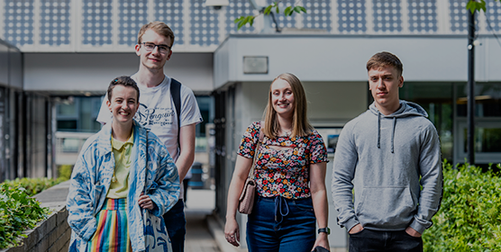 A group of students stood looking directly at the camera - all four of them are smiling