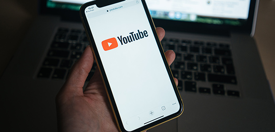 YouTube on mobile phone infront of laptop