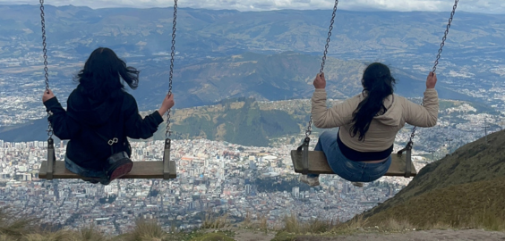 Two people on a swing overlooking a city