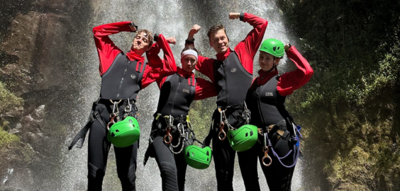 Four people standing in front of a waterfall
