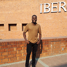 a man standing in front of a brick wall