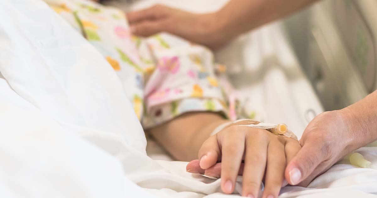 nurse holding ill childs hand 