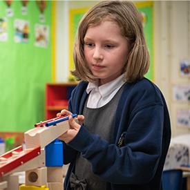 A young girl at school experiments with marbles