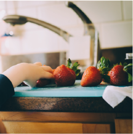Image showing a child's hand reaching for a strawberry