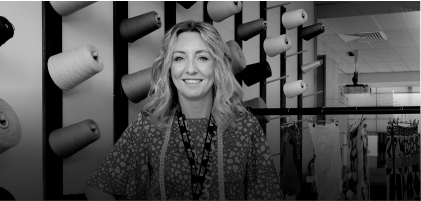 woman smiling in front of reels of ribbon