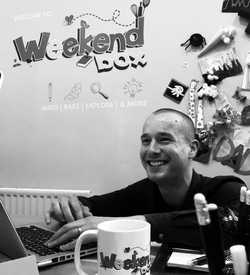 a person sitting at a table with a laptop and smiling at the camera