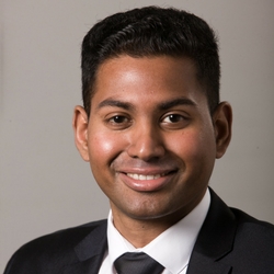 a man wearing a suit and tie smiling at the camera