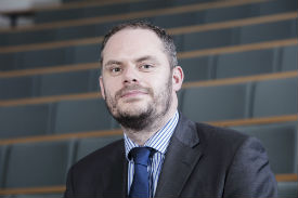 Simon Cole wearing a suit and tie