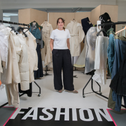Dr Alana James, pictured standing in the middle of two racks of clothing