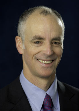 a man wearing a suit and tie smiling at the camera