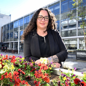 Dr Stephanie Fohring standing next to flowers on Northumbria University's city campus