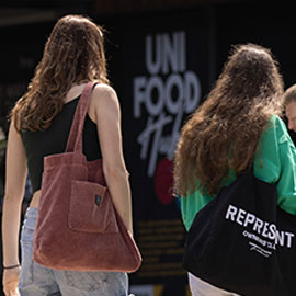 two female students walking past the University Shop. Shop Sign - Uni Food
