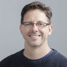 a man wearing glasses and smiling at the camera