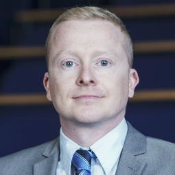 a man wearing a suit and tie smiling at the camera