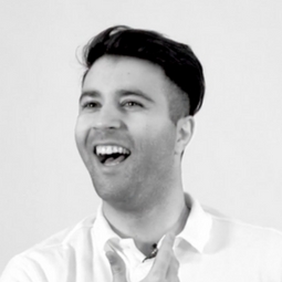 a man wearing a suit and tie smiling at the camera