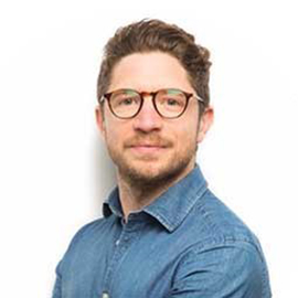 a man wearing glasses and smiling at the camera