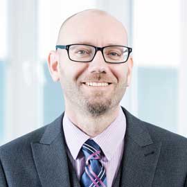 a man wearing a suit and tie smiling at the camera
