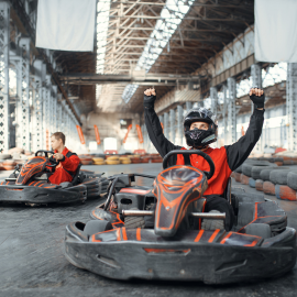 men in go karts hand in air celebrating
