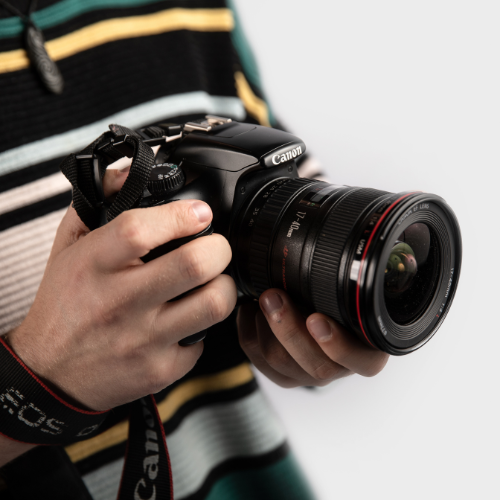 Person in striped jumper, holding a camera.