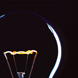 Black background with the outline of a light bulb catching in the light. 