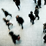 Blurred aerial image of people walking again a white floor. 