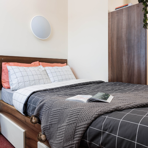 Photograph of a bedroom, the double bed and wardrobe are visible. 