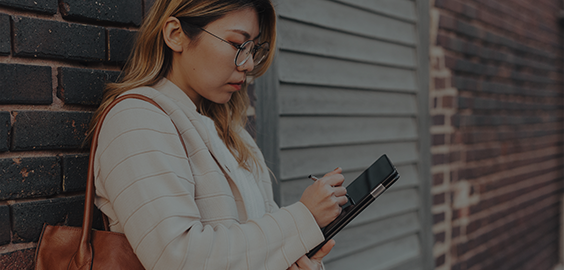 MyPortal: Your Student Portal page menu button -  a student reads information on her tablet while leaning against a wall.