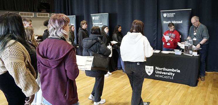 A group of students approach a stand with two advisors
