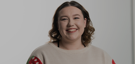 Student wearing cream jumper with red sleeves smiling 