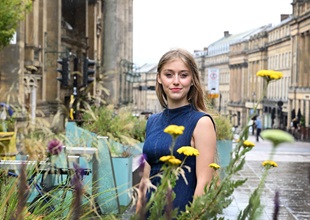 Girl in blue dress standing in Newcastle in front of flowers