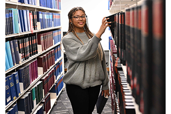 Student getting book from shelf