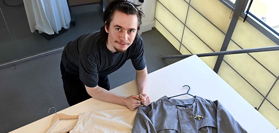 Person standing at a table with clothing items on hangers