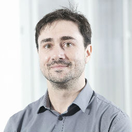 a man wearing glasses and smiling at the camera