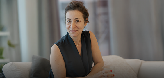 Woman sitting on sofa, smiling and holding drink