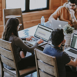 a group of people sitting at a table using a laptop