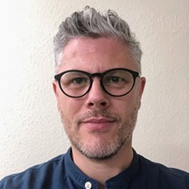 a man wearing glasses posing for the camera