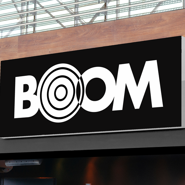 A rectangular sign with the word 'BOOM' in bold white letters on a black background. The first 'O' is replaced by concentric circles, resembling a target.